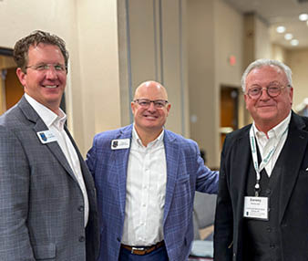 Three men in suits stand together in a room. AI generated content